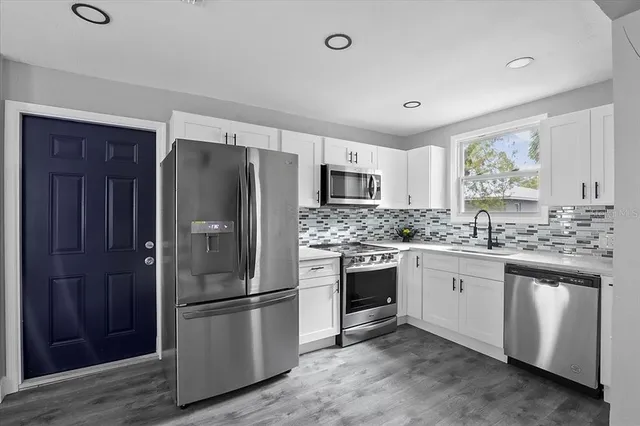 a kitchen with stainless steel appliances granite countertop a refrigerator stove and sink