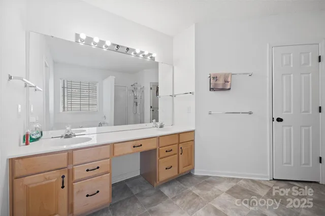 a spacious bathroom with a granite countertop double vanity sink a mirror and shower