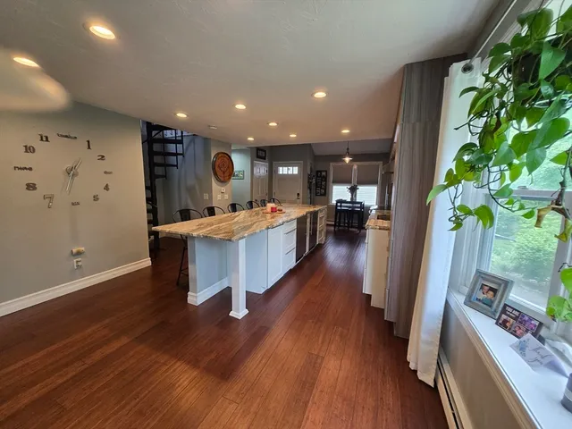 a large kitchen with stainless steel appliances kitchen island a large counter top space a sink and wooden floor