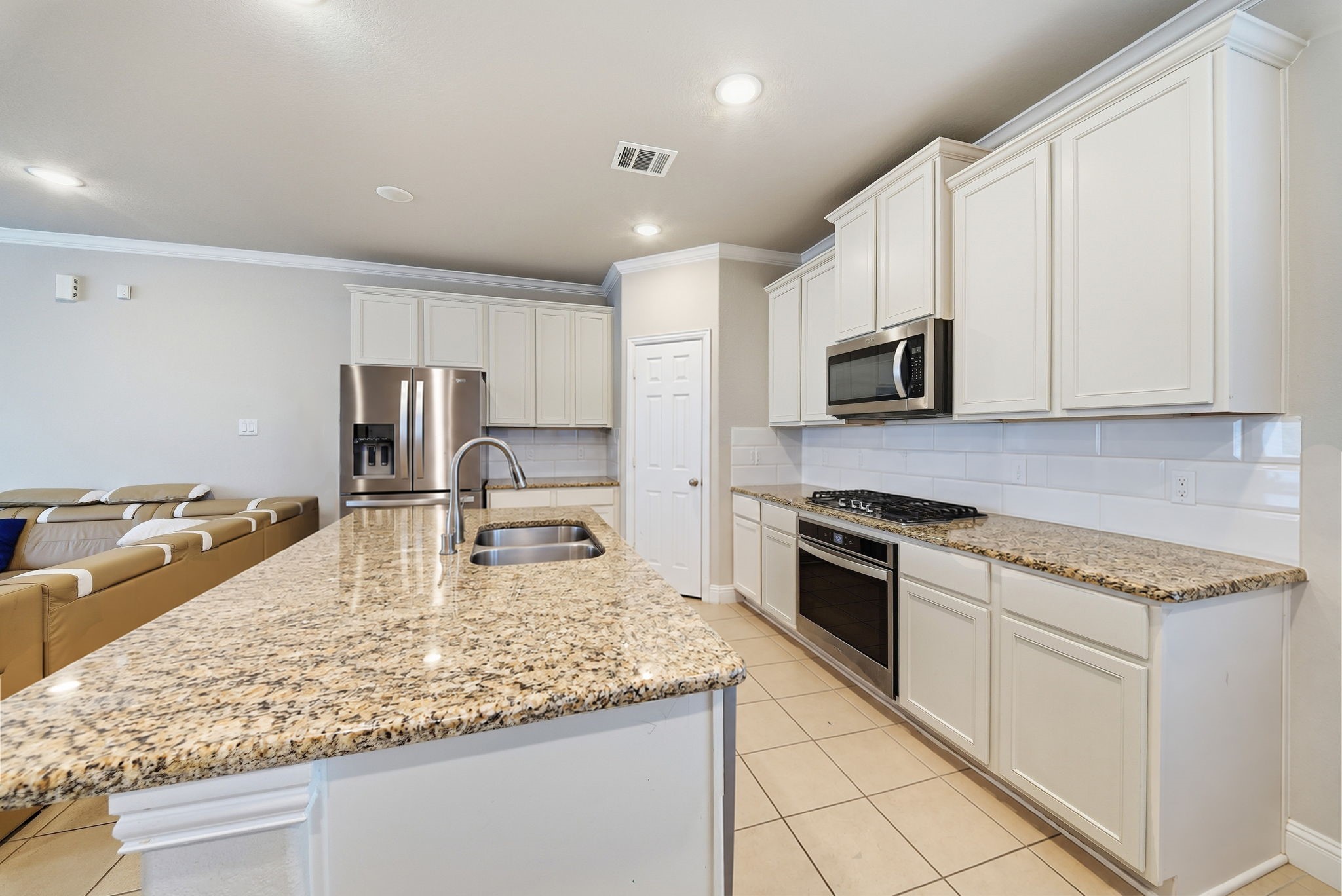 17714 Sugar Magnolia Lane Spring, TX 77379 - Photo 4 of 24 Kitchen with a large island, granite-look counters, white cabinetry, and stainless steel appliances.