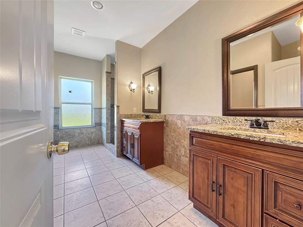 151 Crump Circle Red Oak, TX 75154 - Photo 11 of 21 Full bath with tile walls, wainscoting, two vanities, light tile patterned floors, and a stall shower