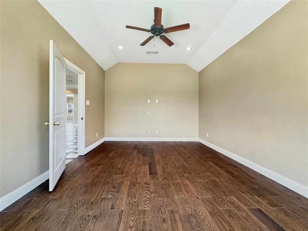 151 Crump Circle Red Oak, TX 75154 - Photo 18 of 21 Empty room with dark wood finished floors, ceiling fan, vaulted ceiling, and recessed lighting