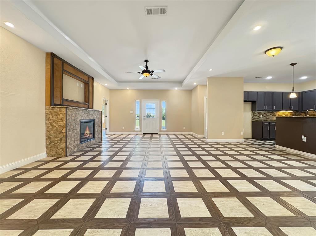 151 Crump Circle Red Oak, TX 75154 - Photo 3 of 21 Unfurnished living room featuring a tray ceiling, a tiled fireplace, a ceiling fan, and recessed lighting