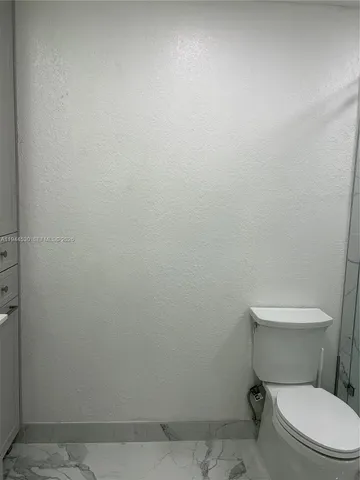 a white toilet sitting next to a white wall
