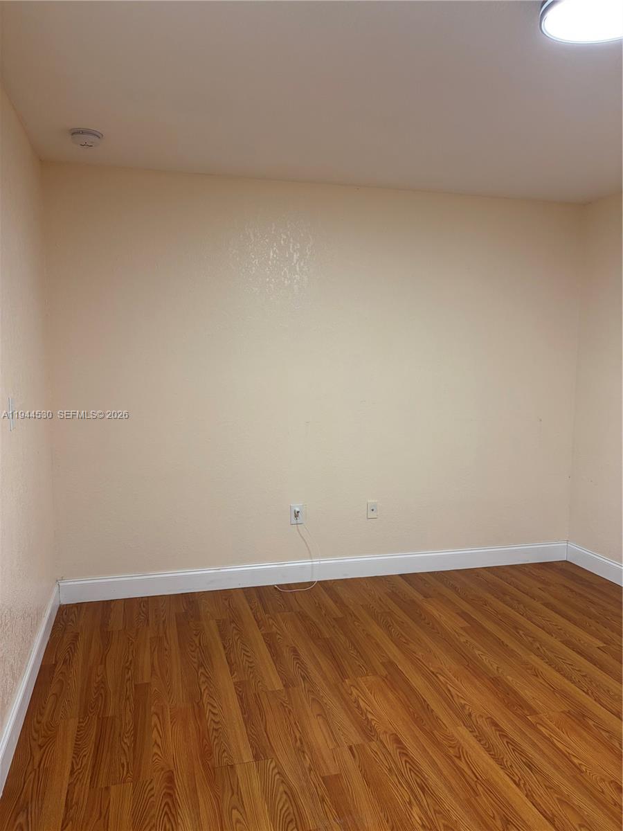 11956 Southwest 209th Street Miami, FL 33177 - Photo 7 of 14 a view of an empty room with wooden floor
