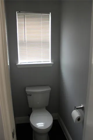 a white toilet sitting in a bathroom next to a window