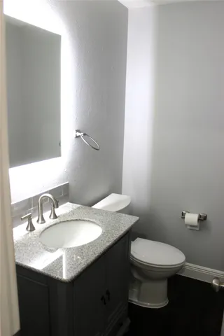a bathroom with a granite countertop sink a toilet and a mirror