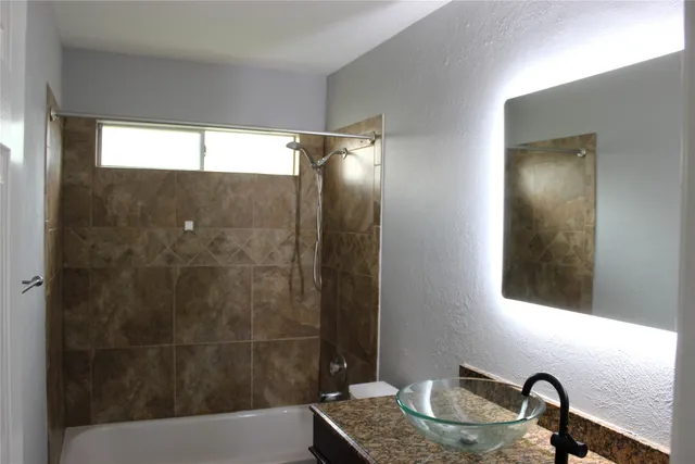 a bathroom with a granite countertop sink mirror and shower