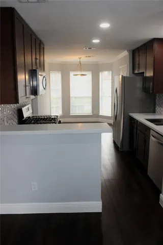 a view of kitchen with wooden floor and black stainless steel appliances