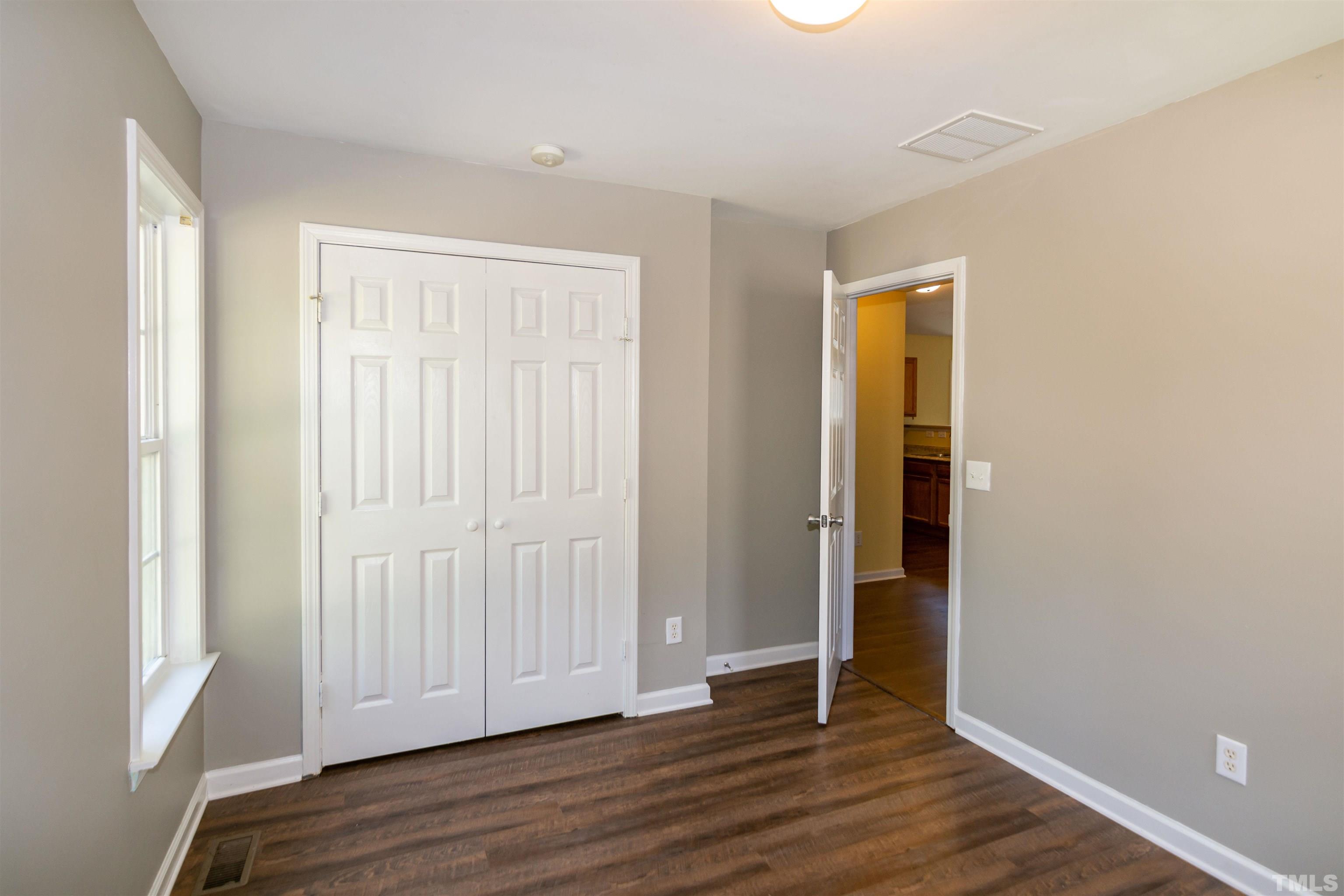 1127 Ricochet Drive Raleigh, NC 27610 - Photo 17 of 21 an empty room with wooden floor and windows