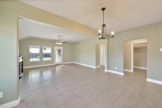 a view of an empty room with window and chandelier