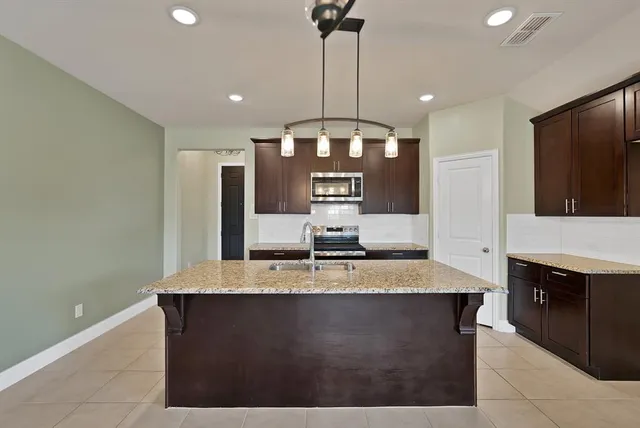 a kitchen with kitchen island granite countertop a sink a counter top space appliances and cabinets