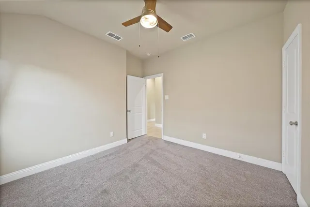 an empty room with chandelier fan and windows
