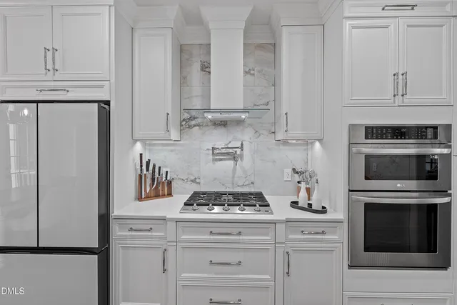a large white kitchen with stainless steel appliances granite countertop a stove and a sink