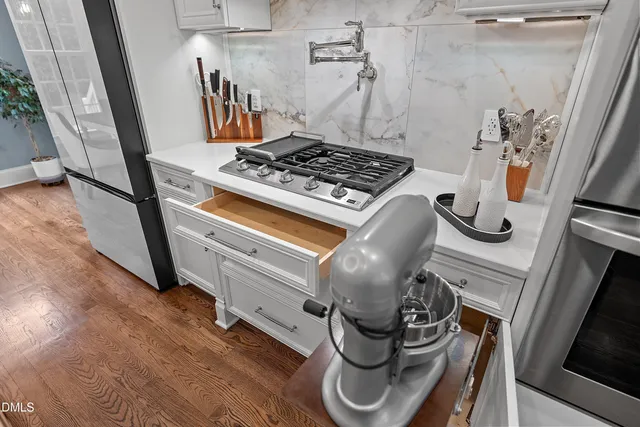 a kitchen with stainless steel appliances a sink dishwasher stove refrigerator and wooden floor