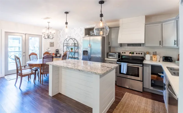 a view of a dining room and livingroom with furniture wooden floor a rug a fireplace and a chandelier
