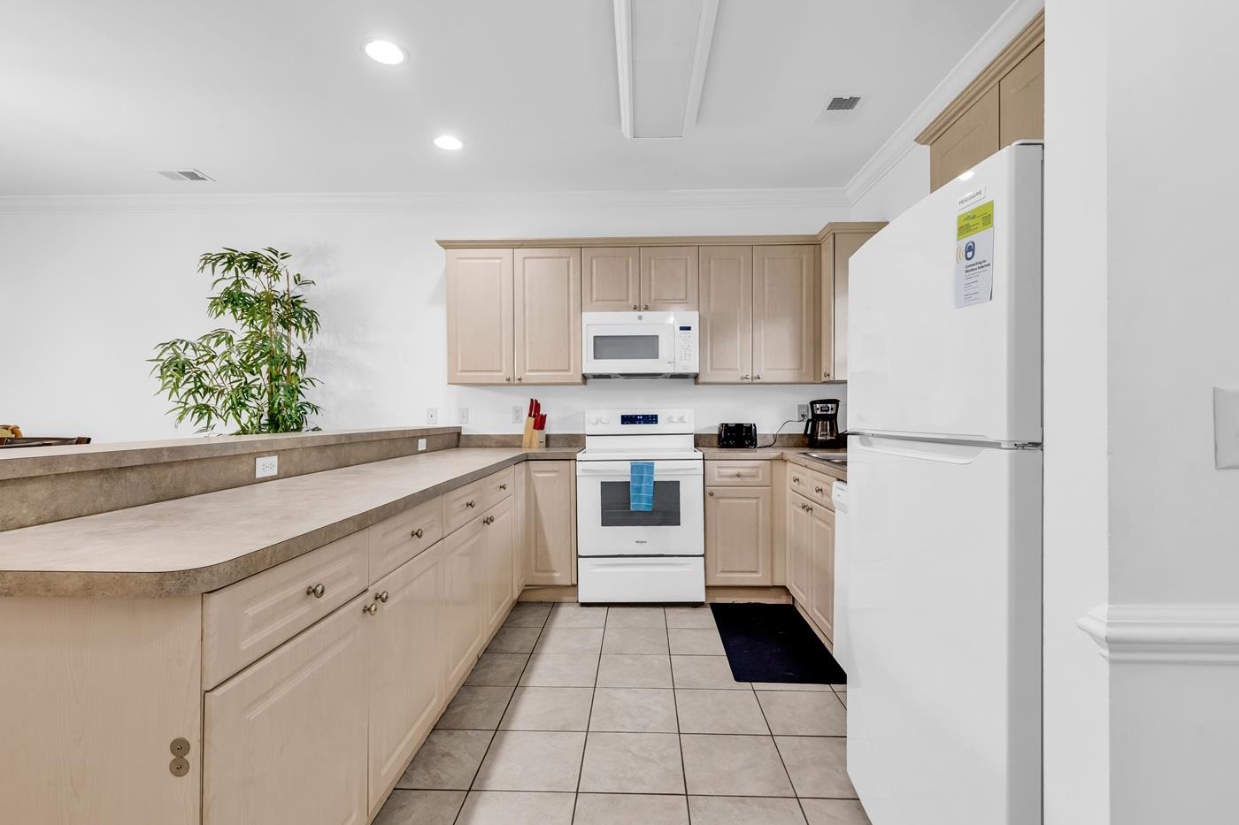 4801 Luster Leaf Circle, Unit 104 Myrtle Beach, SC 29577 - Photo 3 of 37 Kitchen featuring crown molding, white appliances, recessed lighting, light tile patterned flooring, and a peninsula