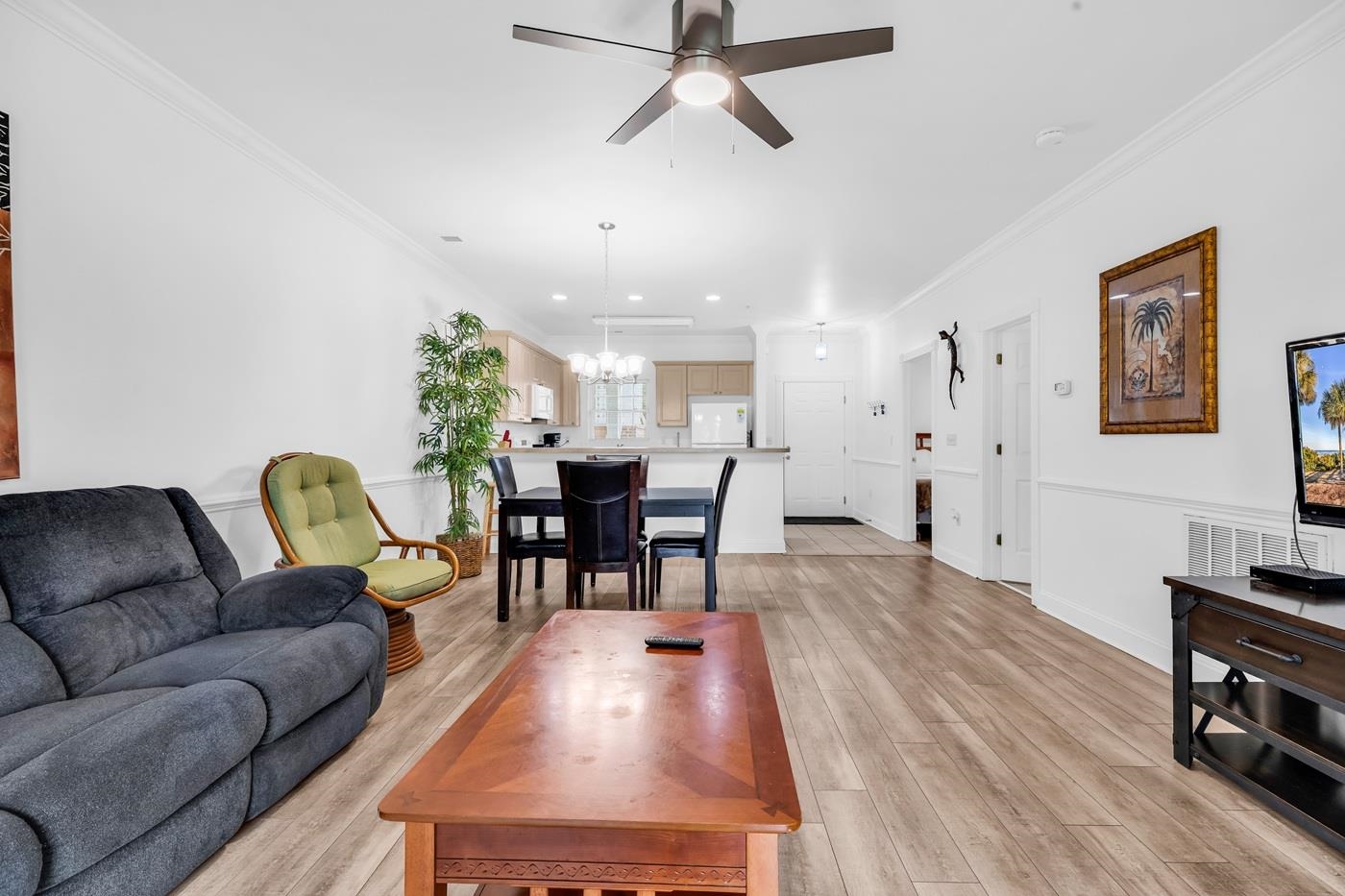 4801 Luster Leaf Circle, Unit 104 Myrtle Beach, SC 29577 - Photo 10 of 37 Living room featuring crown molding, ceiling fan, light wood-style floors, a barn door, and a chandelier