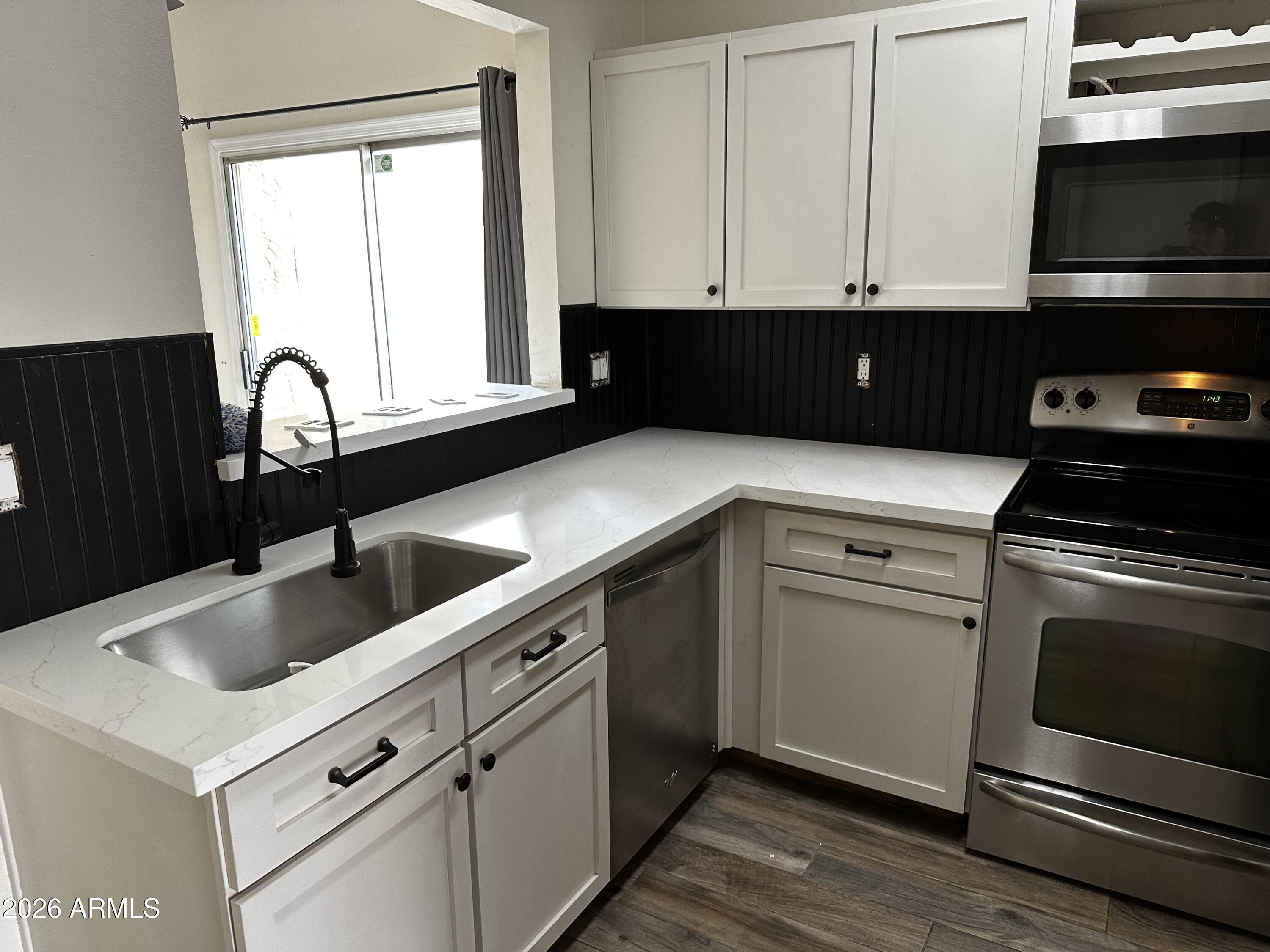 1126 West Elliot Road, Unit 1061 Chandler, AZ 85224 - Photo 4 of 24 a kitchen with granite countertop white cabinets and black appliances