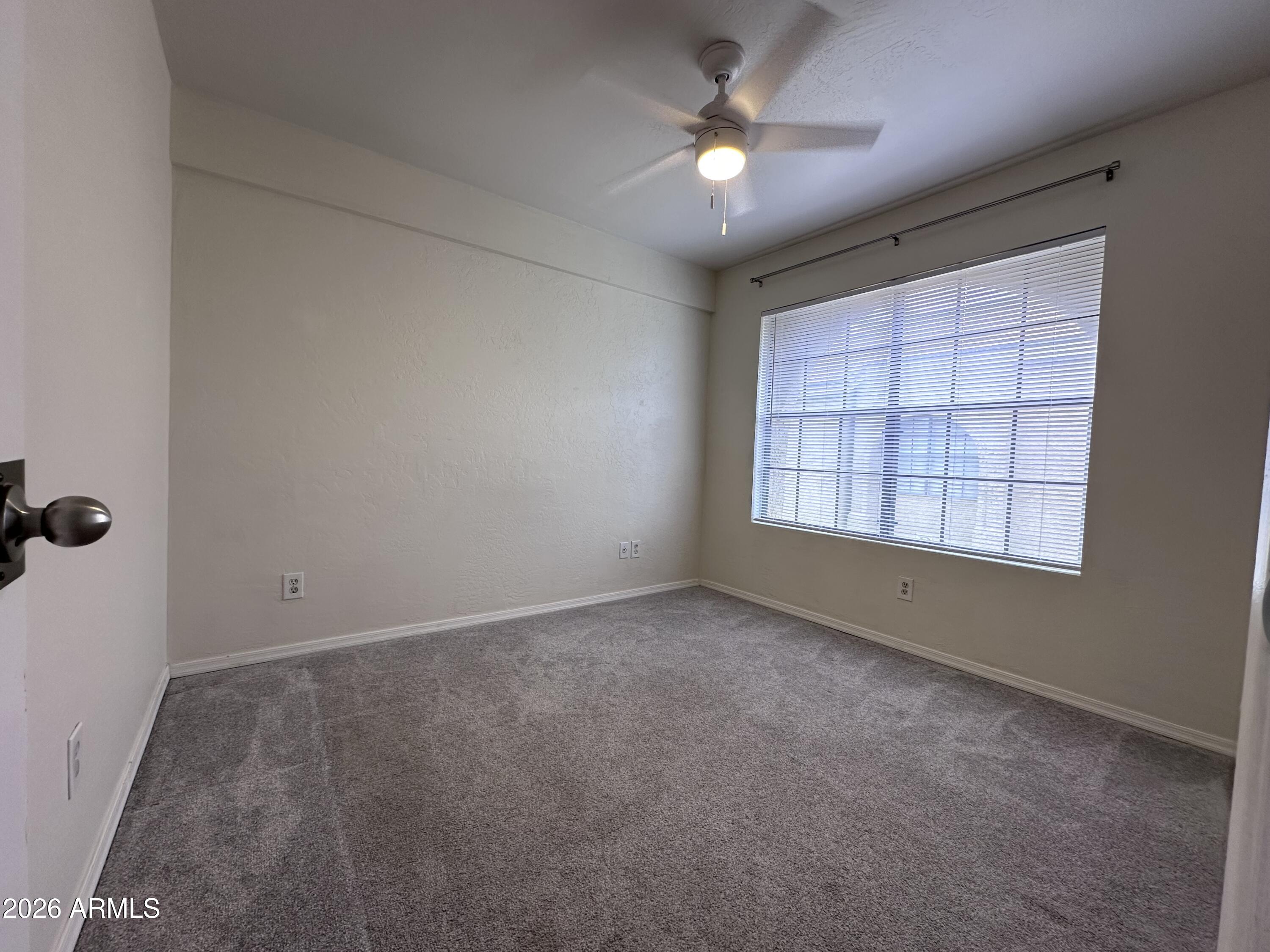 1126 West Elliot Road, Unit 1061 Chandler, AZ 85224 - Photo 9 of 24 an empty room with windows and ceiling fan