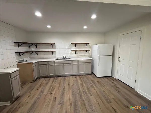 a kitchen with sink a refrigerator and white cabinets