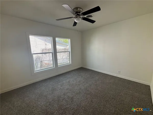 an empty room with a window and a fan