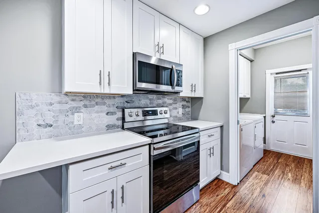a kitchen with cabinets stainless steel appliances and wooden floor
