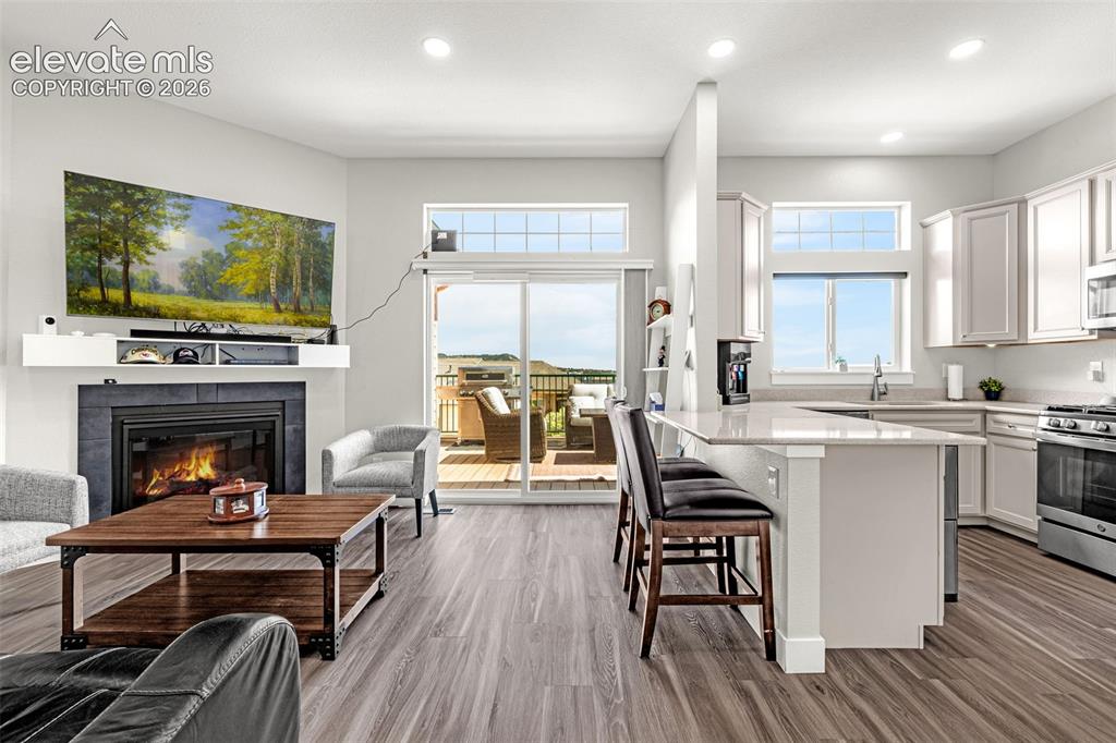 260 Eagle Summit Point, Unit 101 Colorado Springs, CO 80919 - Photo 18 of 33 LVP flooring, living room with gas fireplace, kitchen, and a balcony
