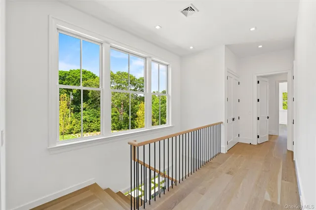 a view of a hallway to a bedroom with a window and wooden floor