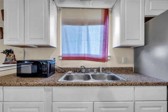 a kitchen with granite countertop white cabinets and a sink
