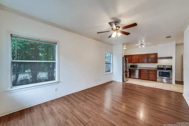 a view of an empty room with a kitchen and wooden floor