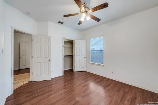 an empty room with wooden floor and ceiling fan