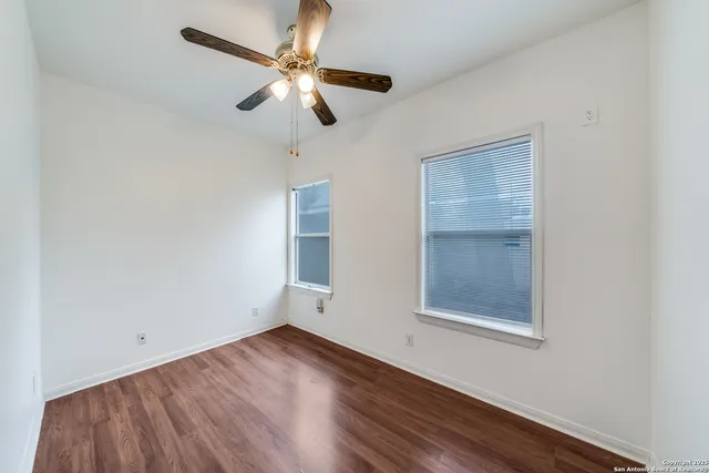 an empty room with a window and a ceiling fan