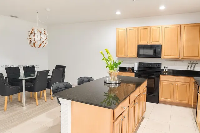 a kitchen with stainless steel appliances granite countertop a stove a sink a microwave a dining table and chairs with wooden floor