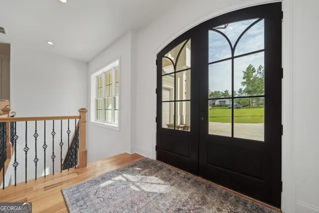 a kitchen with stainless steel appliances granite countertop a sink a stove a refrigerator and white cabinets with wooden floor