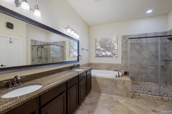 a bathroom with a granite countertop bathtub a double vanity sink and mirror