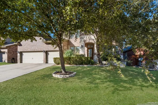 a front view of a house with a yard and tree