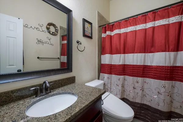 a bathroom with a sink a toilet and shower curtain