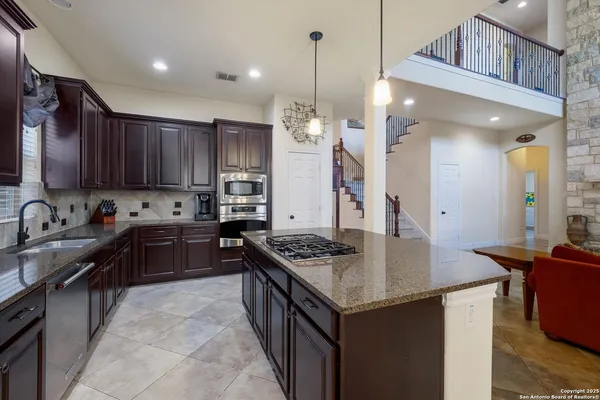 a kitchen with granite countertop a sink stove and refrigerator