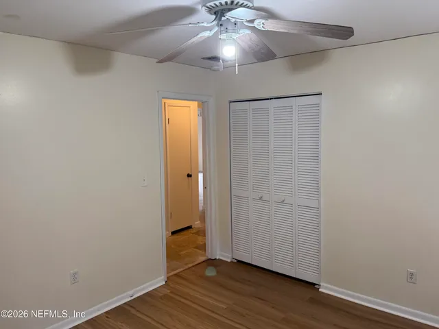 an empty room with wooden floor and ceiling fan