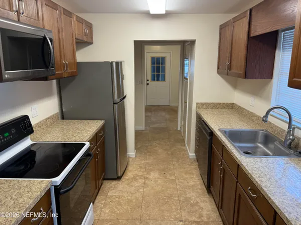a kitchen that has a sink a microwave a refrigerator and wooden cabinets