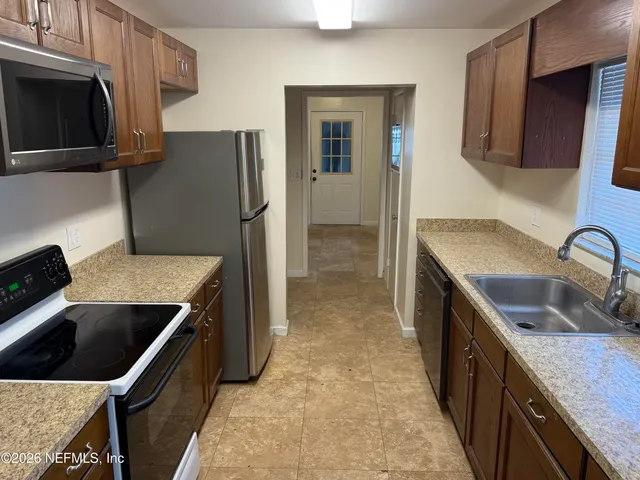 a kitchen that has a sink a microwave a refrigerator and wooden cabinets