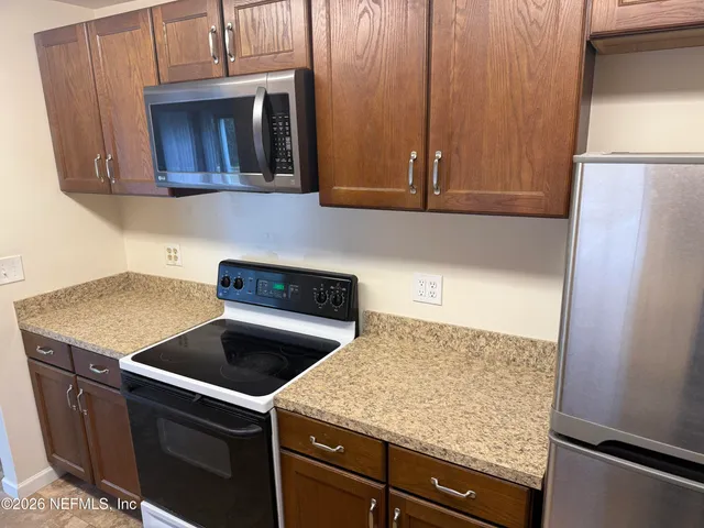 a kitchen with granite countertop wood cabinets and a stove