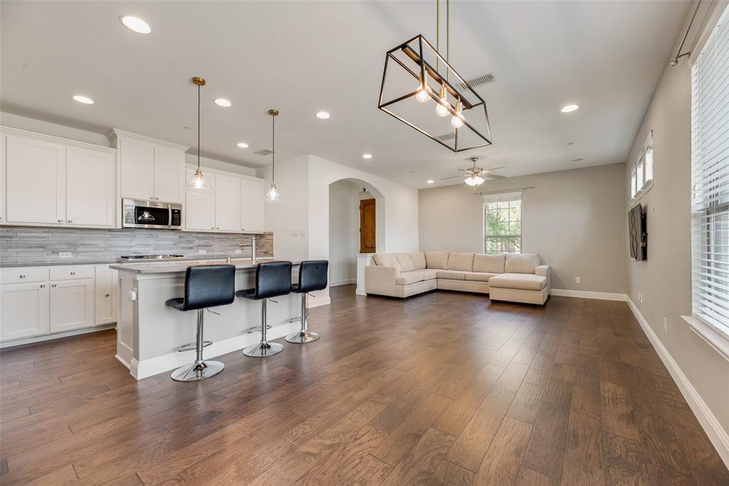 4670 I Rhett Lane, Unit I Carrollton, TX 75010 - Photo 9 of 31 Open concept living space featuring wood-finish flooring, white cabinetry, a kitchen island with seating, pendant lighting, and recessed ceiling lights