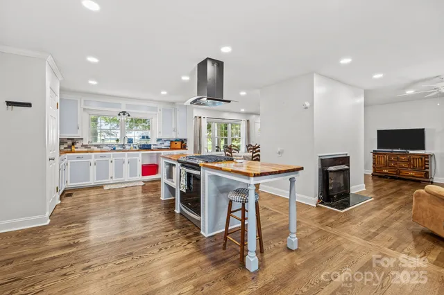 a living room with stainless steel appliances furniture a fireplace a flat screen tv and view kitchen