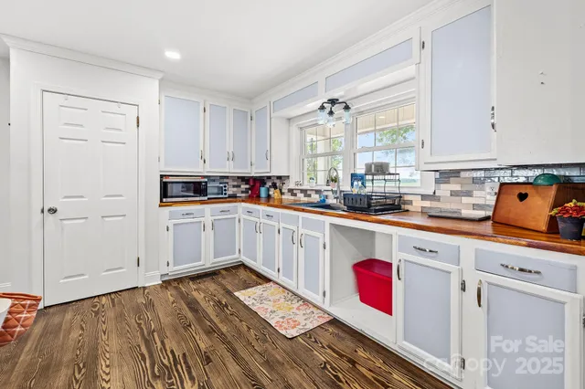 a kitchen with a sink wooden floor and white appliances