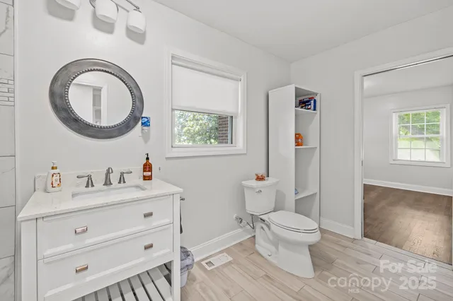 a bathroom with a toilet a sink a mirror and a window