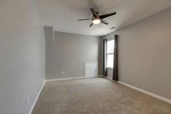 an empty room with a chandelier fan and windows