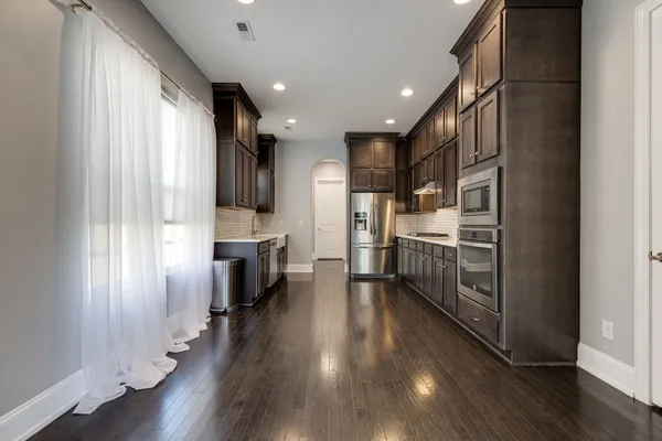 a view of a kitchen with refrigerator and wooden floor
