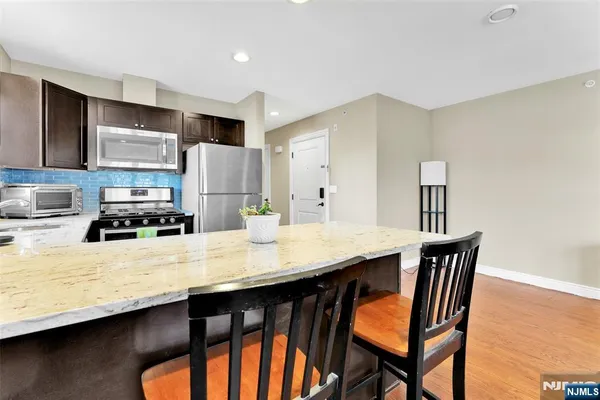 a kitchen with stainless steel appliances granite countertop a table chairs sink and cabinets